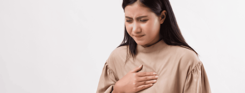 Chica con su mano apoyada en el pecho por un dolor en el pecho